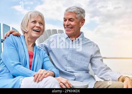 Love makes everyday extra special. an affectionate senior couple relaxing on chairs together outside. Stock Photo