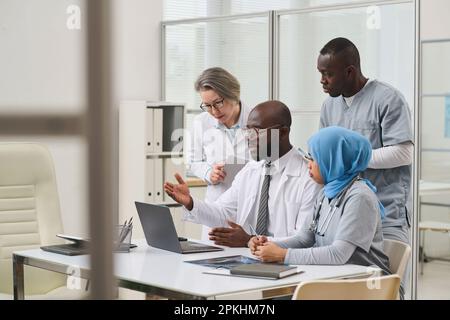 Group of professional doctors using laptop in their teamwork at table during business meeting in office Stock Photo