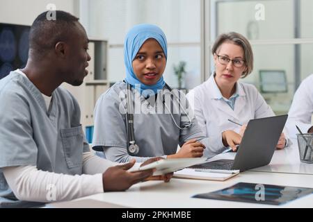 Female doctor showing x-ray image on laptop to her colleagues and discussing disease of patient with her colleagues during a meeting Stock Photo
