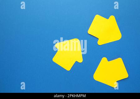 Paper sticky notes in shape of arrow on blue background. Top view Stock Photo