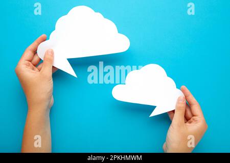 Two hands holding up speech bubbles on blue. Top view Stock Photo