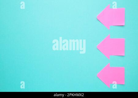 Paper sticky notes in shape of arrow on blue background. Top view Stock Photo