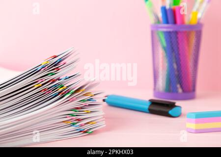 White paper with multicolored clips and stationery on pink. Top view Stock Photo