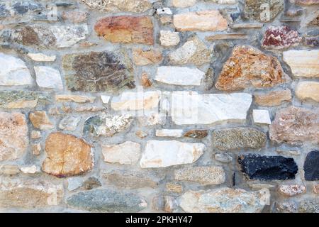 Empty stonewall various color stone with grey cement background texture. Vintage rocky wall, blank masonry or floor backdrop. Copy space. Stock Photo