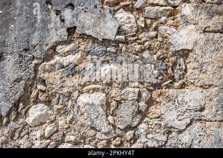 Empty aged stonewall material background texture. Old, worn, distressed stone wall structure, plaster and peeled paint layer. Copy space. Stock Photo