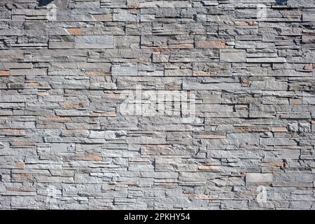 Empty slate stone wall background texture. Granite masonry, mosaic construction, solid strong grey fence structure. Copy space Stock Photo