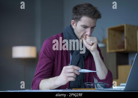 Unhealthy looking young male entrepreneur in warm knitted scarf around his neck coughing looks at digital thermometer in his hand not believing that c Stock Photo