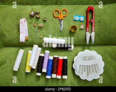 Sewing kit flat lay including spools of thread, scissors, measuring tape, buttons, needles. Tailor or seamstress equipment top view Stock Photo