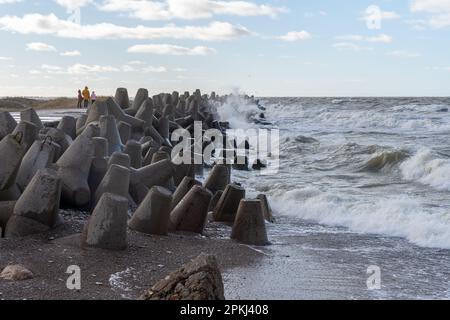 Waves crashing against breakwater consisting of gray concrete tetrapods. Liepaja, Latvia. Liepājas Ziemeļu mols Stock Photo