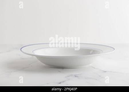 Empty white soup plate with blue stripe on a white background Stock Photo