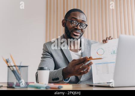 Young smiling african businessmen discussing income with partner via video call on laptop, pleasant afro american male ceo executive talking about pro Stock Photo