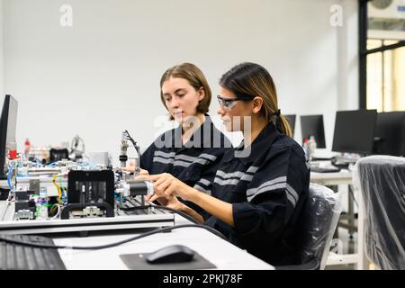 Happy engineers using laptop checking and operating robotic machine Stock Photo