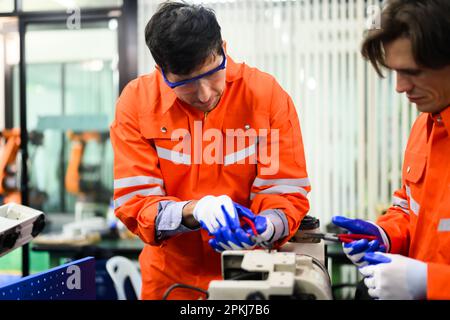 Engineers working and solving problems on machine at industrial plant Stock Photo