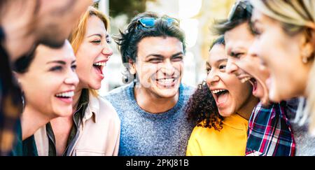 Trendy friends cheering together out side on genuine life style concept - Young guys and girls having fun hugging around city streets vacation Stock Photo