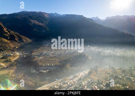 aerial drone shot gaining height over fog covered valley town of manali hill station with himalaya range in distance showing this popular tourist Stock Photo