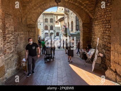 alleyway in the old town of San Gimignano with tourists - San Gimignano, Siena province,Tuscany,Italy - June 2, 2021 Stock Photo