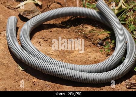 Piece of PVC Flexible Corrugated Hose Pipe used for Cable Protection or for plumbing placed on the ground Stock Photo