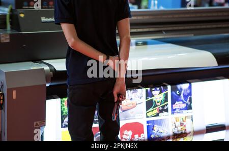 Bangkok, Thailand - March 31, 2023: Man checking print quality in Print Tech 2023 Stock Photo