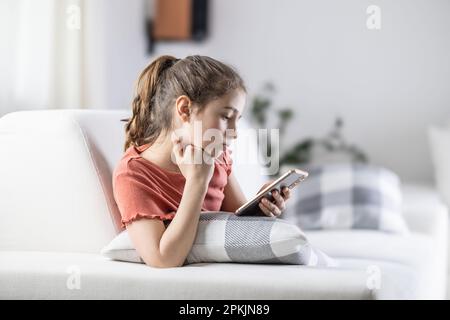 Young generation always on their phones represented by a girl at home with a cellphone in her hand. Stock Photo