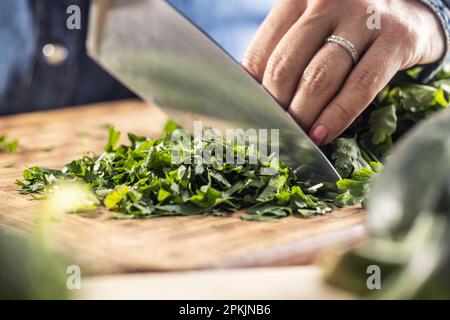 Green fresh parsley cut on a wooden board by a sharp knife. Stock Photo