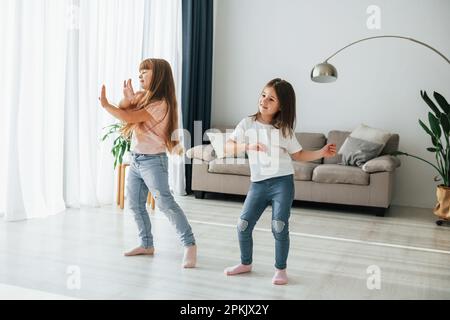 Dancing together. Kids having fun in the domestic room at daytime Stock Photo
