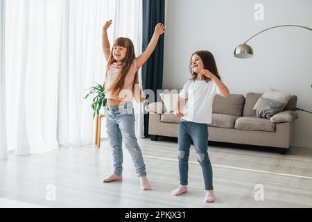 Dancing together. Kids having fun in the domestic room at daytime Stock Photo