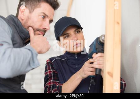 carpenter using a drill on a wood house structure Stock Photo