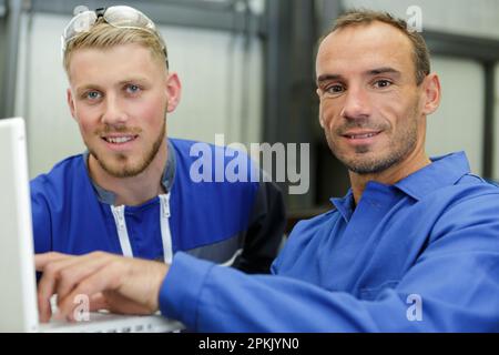 two engineers wearing overalls using laptop Stock Photo
