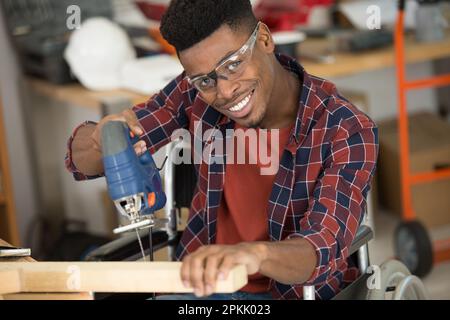 a man carpenter cuts a wooden beam using a jigsaw Stock Photo