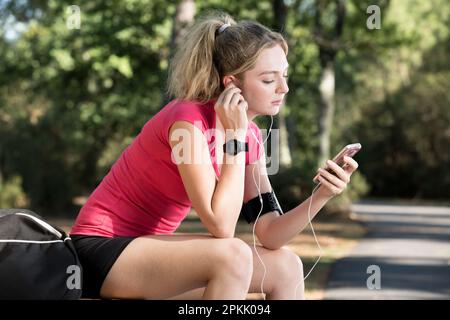 young smiling woman with sporty clothes listening to music Stock Photo