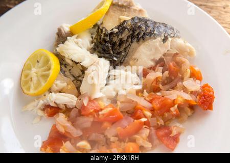 A cooked Black Tilapia, Oreochromis niloticus, imported to the UK from Indonesia. It has been baked in foil with butter, tomatoes, red nions, garlic a Stock Photo