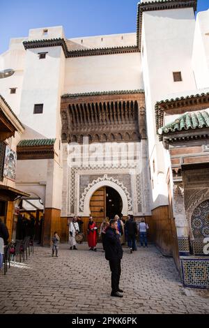 People stream out of an arched doorway in Fez Medina Morocco Stock Photo