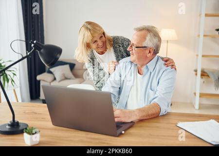 Using laptop. Senior man and woman is together at home. Stock Photo