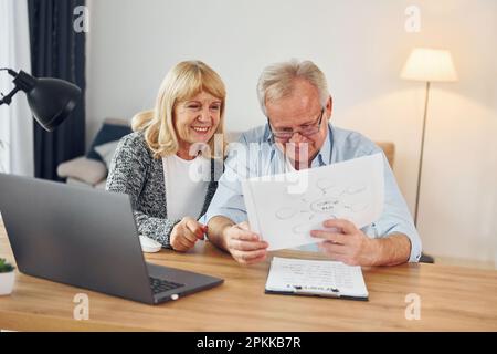 Using laptop. Senior man and woman is together at home. Stock Photo