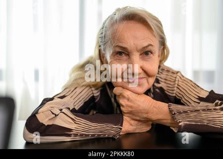 Smiling portrait of healthy senior woman smiling and sitting at home Stock Photo