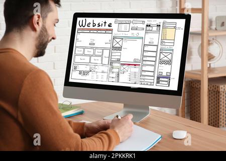 Designer creating website on computer at wooden table Stock Photo