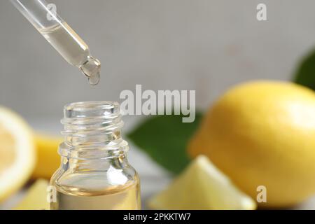 Citrus essential oil dripping from pipette into bottle, closeup. Space for text Stock Photo