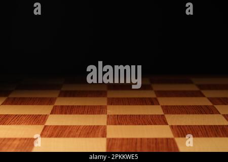 Checkered chessboard on dark background, closeup view Stock Photo