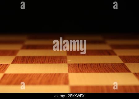 Checkered chessboard on dark background, closeup view Stock Photo