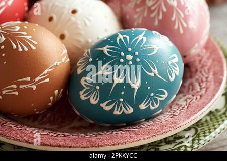 Colorful Easter eggs with wax ornaments on a red plate Stock Photo