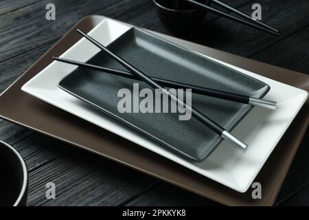 Stylish sushi dishware and chopsticks on black wooden table, closeup Stock Photo