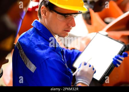 Expertise technician using digital tablet working at industrial plant Stock Photo