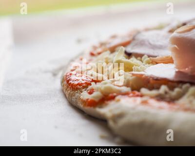 raw pizza dough with cheese, ham and sauce. pizza preparation Stock Photo