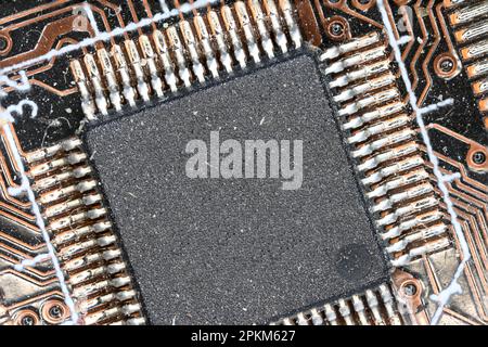 brown computer board extreme closeup view with visible solder joints and a big chip offering copy space as a concept for PC microelectronic electronic Stock Photo