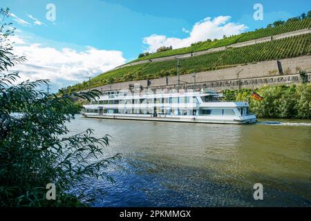 Recreational boat in Mid September with small quantity  of passengers and vineyards  on hillsides in Wurzburg.   Ship with German flag and blurred mot Stock Photo