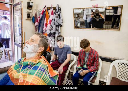 An American tourist getting a straight razor shave at a barbershop in Marrakech Morocco Stock Photo