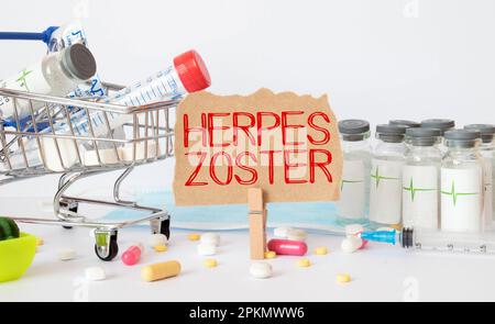 On the sheets for notes the text herpes zoster, next to red and green capsules Stock Photo