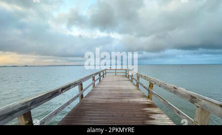 Empty wooden pier to the Ria de Aveiro in Portugal, with dramatic sky and calm water. Torreira, Murtosa - Portugal. Stock Photo