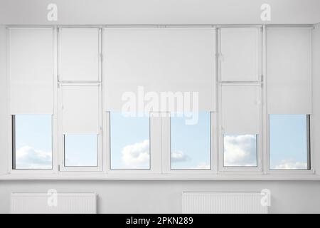 Plastic windows with white roller blinds indoors Stock Photo