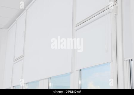 Plastic windows with white roller blinds indoors Stock Photo